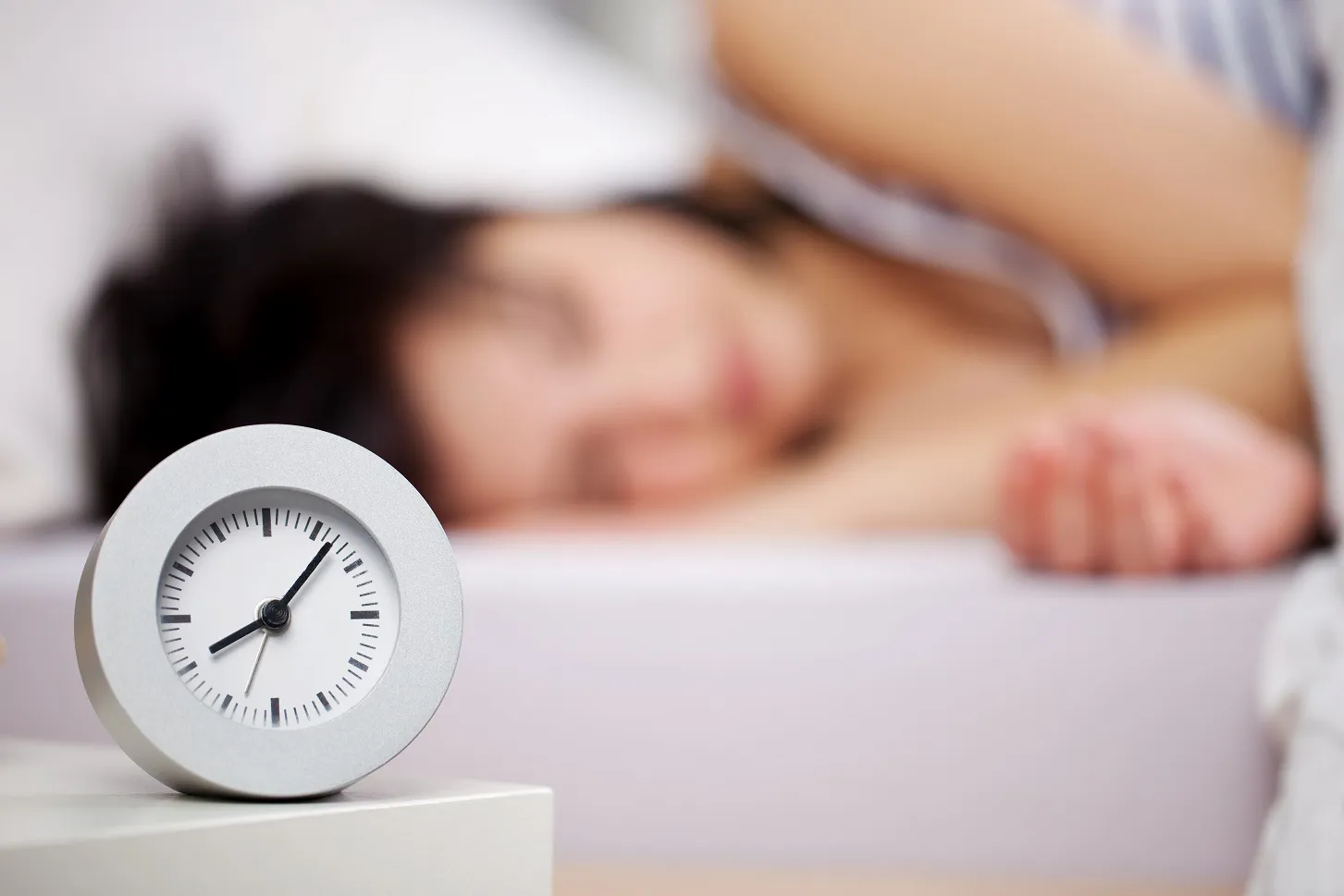 En person som sover med en klokke på nattbordet