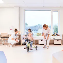 Flere barn og to sykepleiere leker i et lekerom